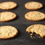 Momofuku Milk Bar's Corn Cookies on a baking sheet. One cookie has a bite taken out of it.