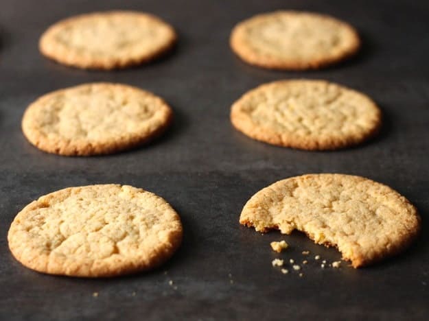 Momofuku Milk Bar's Corn Cookies on a baking sheet. One cookie has a bite taken out of it.