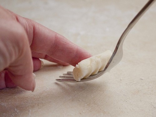 Rollen Sie glutenfreie Gnocchi auf einem Löffel.