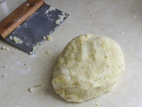 Massa de gnocchi sem glúten no balcão com um raspador sentado atrás dele.