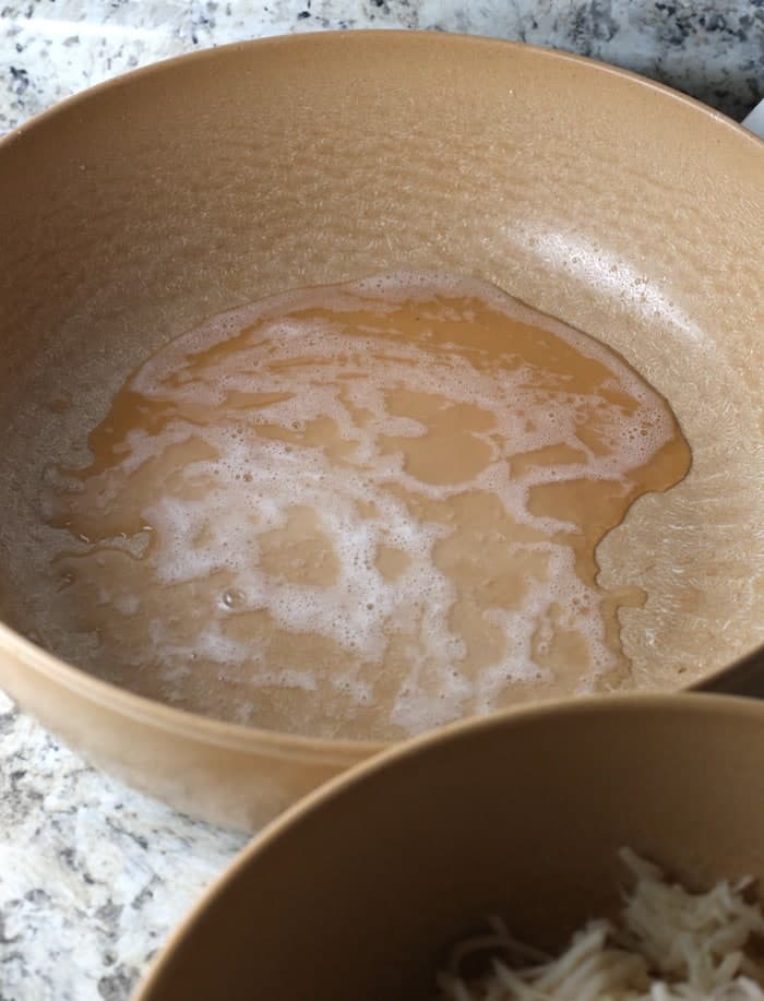 Liquid from drained potatoes in a brown bowl.