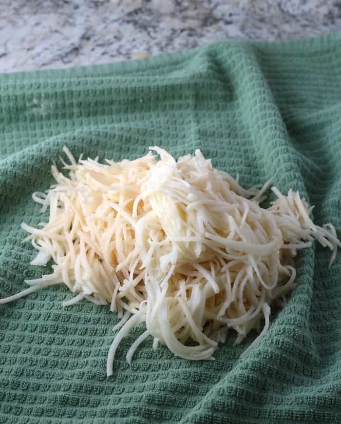 Shredded potatoes on a green towel.