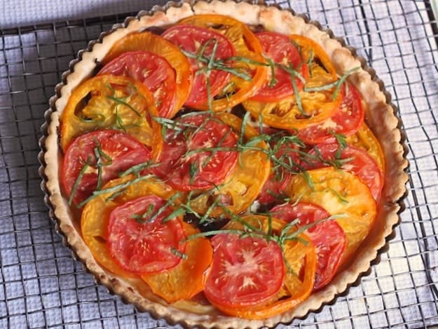 Gluten-Free Tomato Tart on a wire rack. The tart is topped with shredded basil.