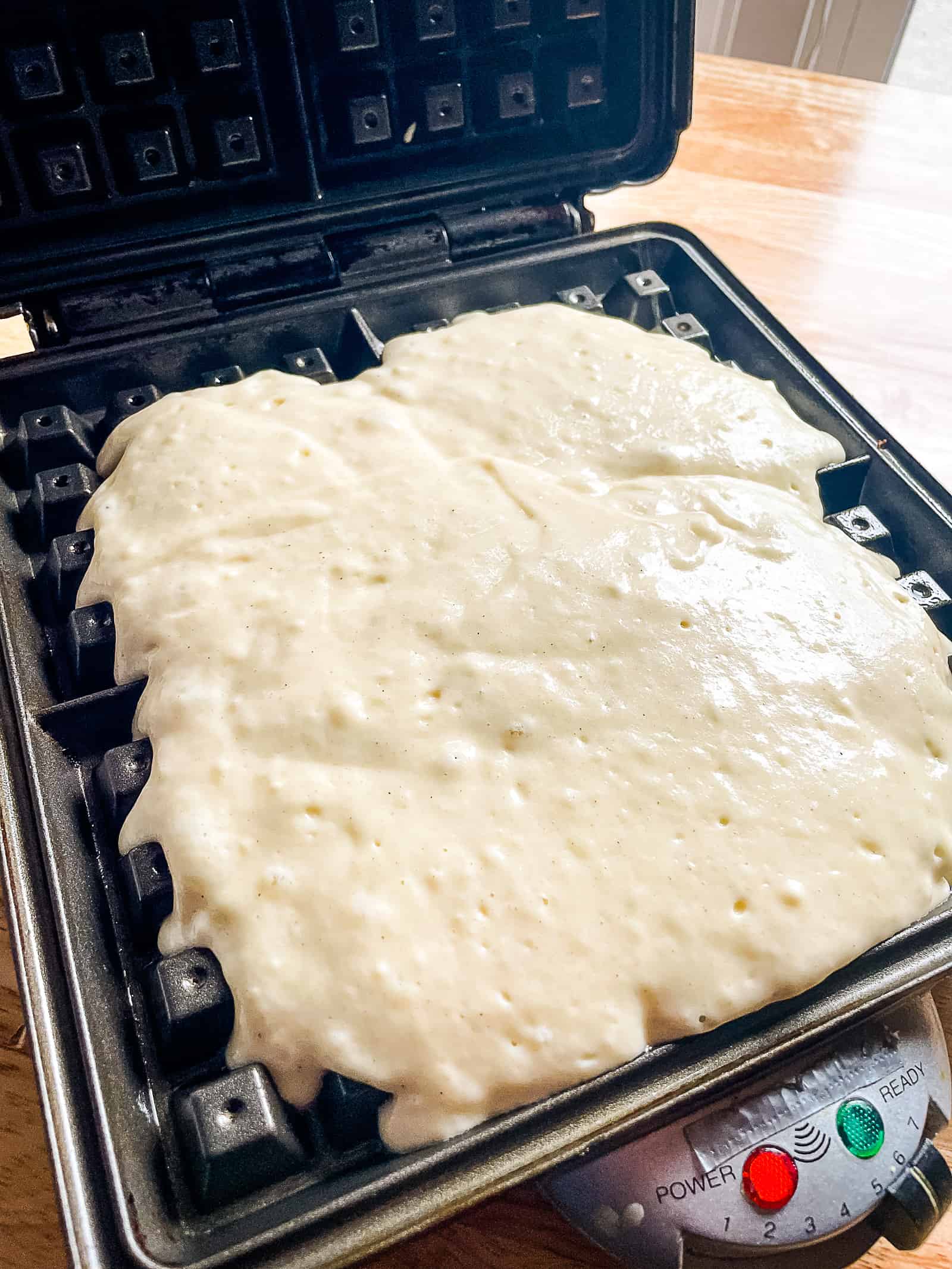 Gluten free waffle batter in a waffle maker.