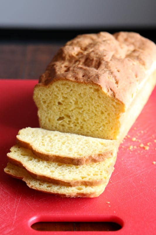 Gluten-free sandwich bread, sliced on a red cutting board.