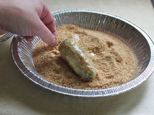 Rolling jalapeño pepper in gluten-free breadcrumbs.