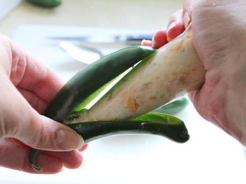 Filling jalapeño pepper with cream cheese filling.