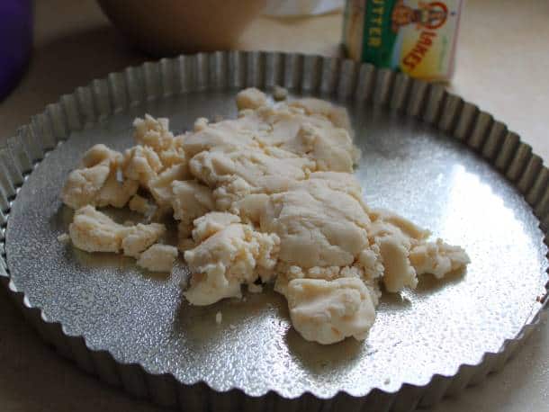 Gluten-free tart dough piled into the center of the pan before being pressed out.