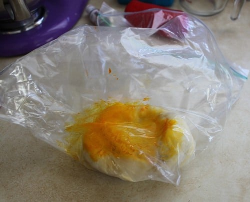 Gluten-free cookie dough in a plastic bag being dyed yellow.
