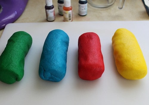 Four logs of gluten-free cookie dough dyed green, blue, red, and yellow.