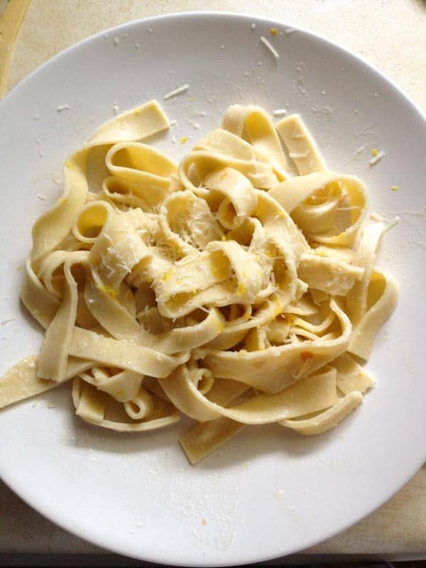 Fresh Gluten-Free Pasta topped with Parmesan and lemon on a white plate.