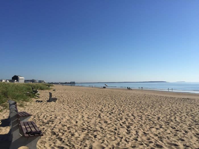 Sandy beach with blue sky. Two benches on the beach.