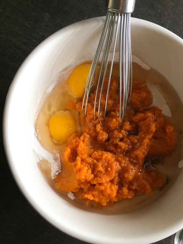 Whisking pumpkin puree, eggs, and oil in bowl.