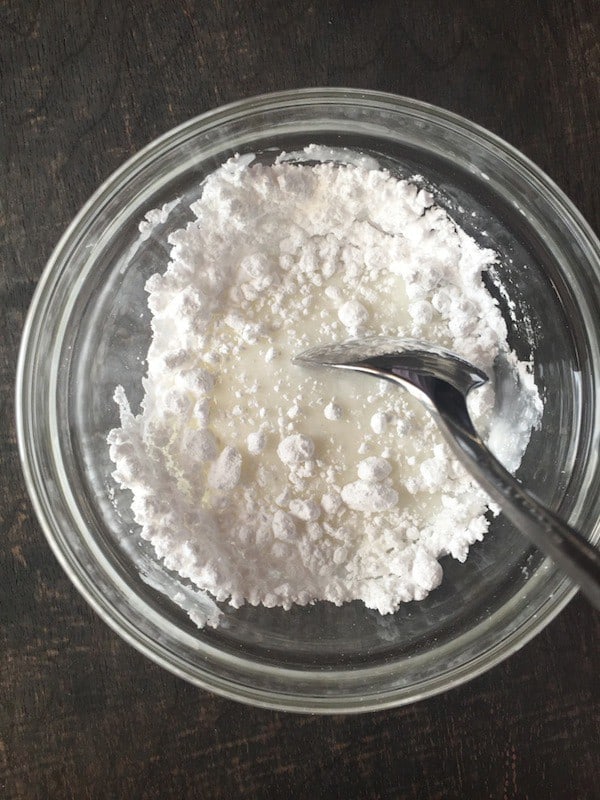 Powdered sugar and milk being mixed together.