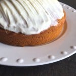 Gluten-free pumpkin cake frosted with cream cheese frosting on white platter.