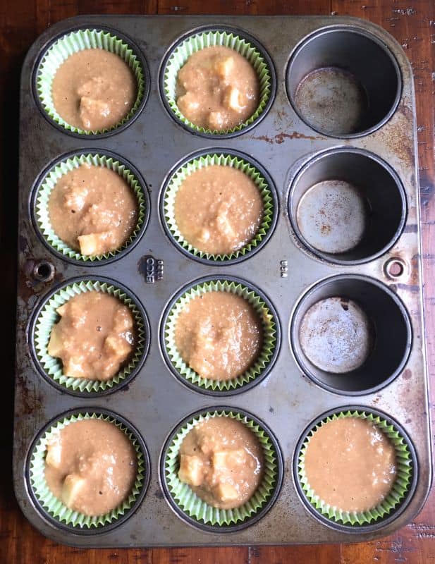 Paleo apple muffins in a pan lined with paper liners.