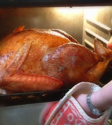 Turkey being taken out of oven.