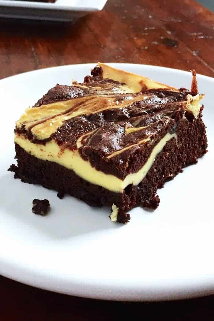 Gluten-free cheesecake brownie on white plate.