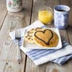 Paleo Marble Pancakes on plate. Coffee, orange juice, and a bottle of syrup sit behind the plate.