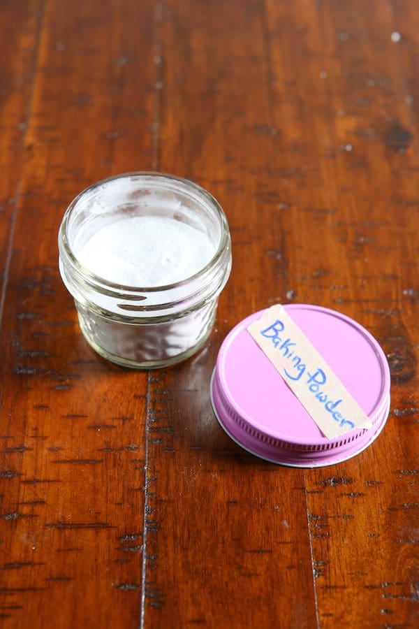 Jar of baking powder with lid off. Pink lid is labeled with white tape that says, "Baking powder."