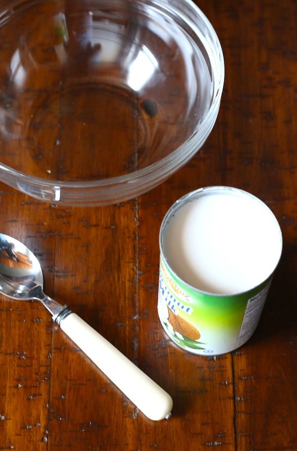 Can of whipped coconut milk sitting next to a glass bowl and spoon.