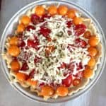 Unbaked gluten-Free tomato pie topped with shredded cheese.
