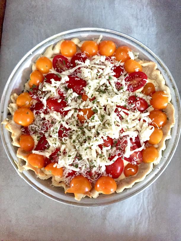 Unbaked gluten-Free tomato pie topped with shredded cheese.