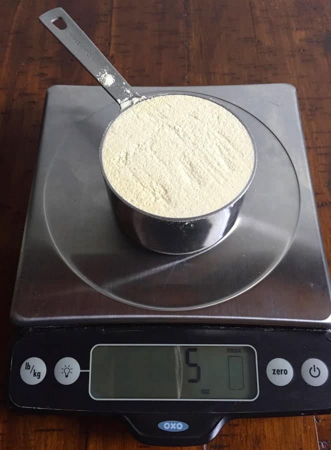 Cup of brown rice flour on a digital scale. Display reads 5 ounces.