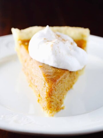Gluten-Free Sweet Potato Pie topped with whipped cream on a white plate.