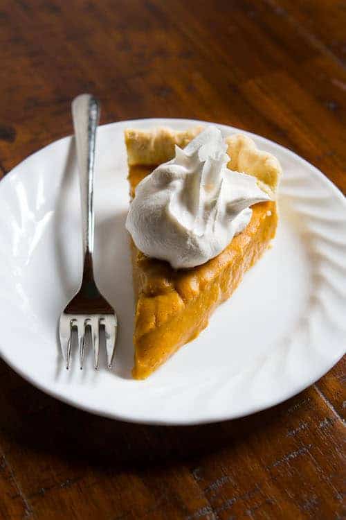 Egg-free, dairy-free, gluten-free pumpkin pie on plate with whipped cream.
