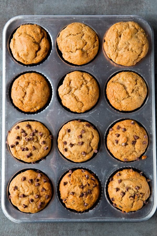 Gluten-free banana muffins in pan. Half are topped with chocolate chips.