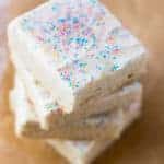Stack of gluten-free sugar cookie bars. Frosted with vanilla frosting and topped with sprinkles.