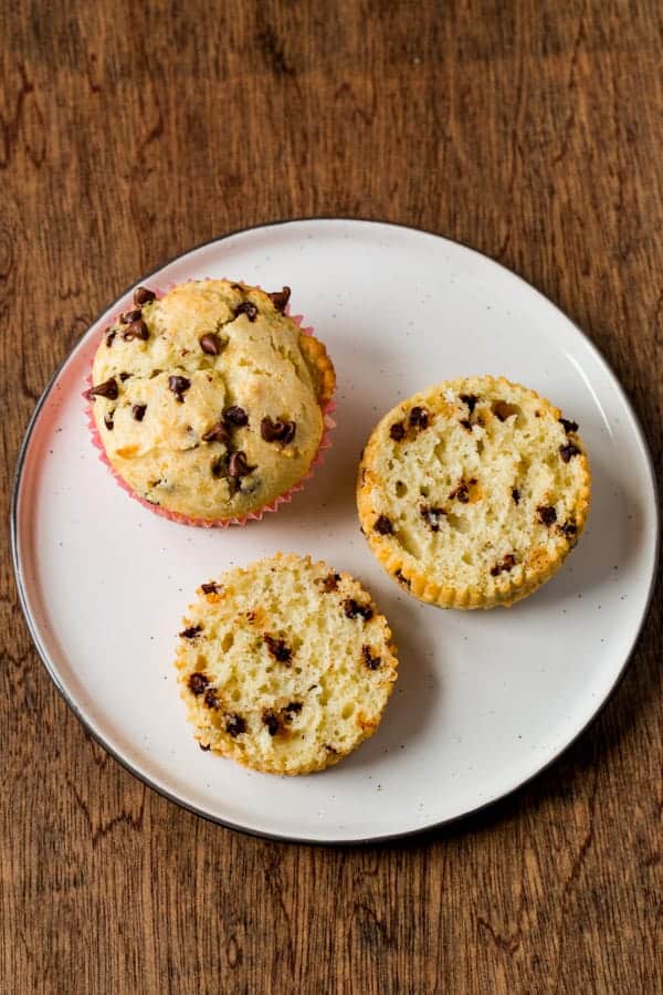 Gluten-free chocolate chip muffins on plate. One is split to show texture.