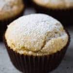 Gluten-free sour cream muffins topped with powdered sugar. One is split to show texture.