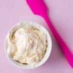 Gluten-Free Vanilla Buttercream Frosting in a white bowl with a pink spatula next to it.