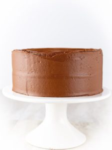 Gluten-Free Chocolate Cake on a white cake stand.