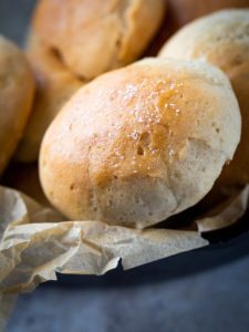 Gluten-free soft rolls in basket. Top of roll is sprinkled with kosher salt.