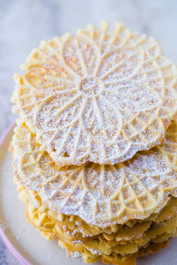 Stack of Baked Pizzelles Dusted with Powdered Sugar.