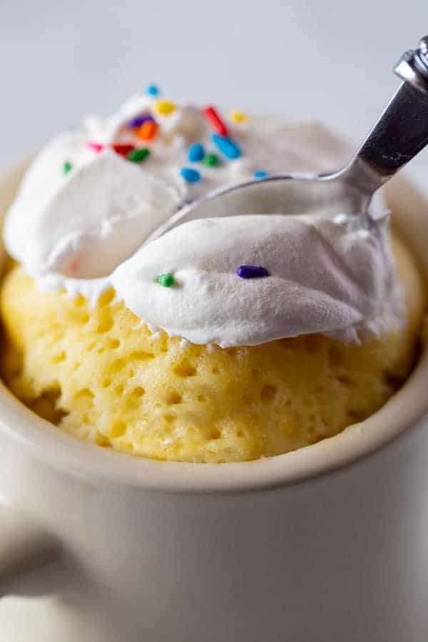 Gluten-Free Mug Cake in White Mug. Topped with Whipped Cream and Sprinkles