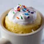 Gluten-Free Mug Cake in White Mug. Topped with Whipped Cream and Sprinkles