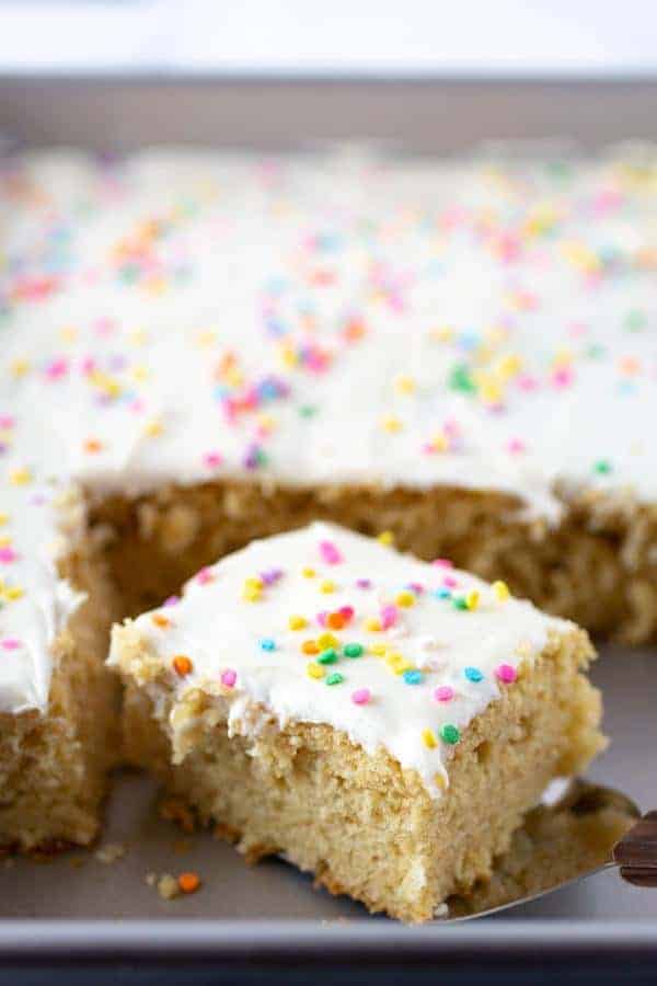 Gluten-Free Vanilla Sheet Cake. Sliced in Pan. Frosted with Vanilla Frosting and sprinkled with pastel sprinkles. 