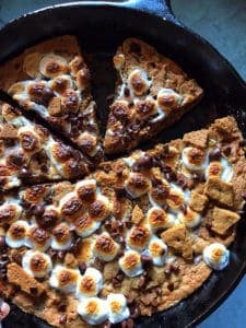 Gluten-Free S'more Cookie in Skillet. Cut and topped with browned marshmallows and chocolate chips.