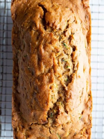 Loaf of baked gluten-free zucchini bread on a cooling on a rack.