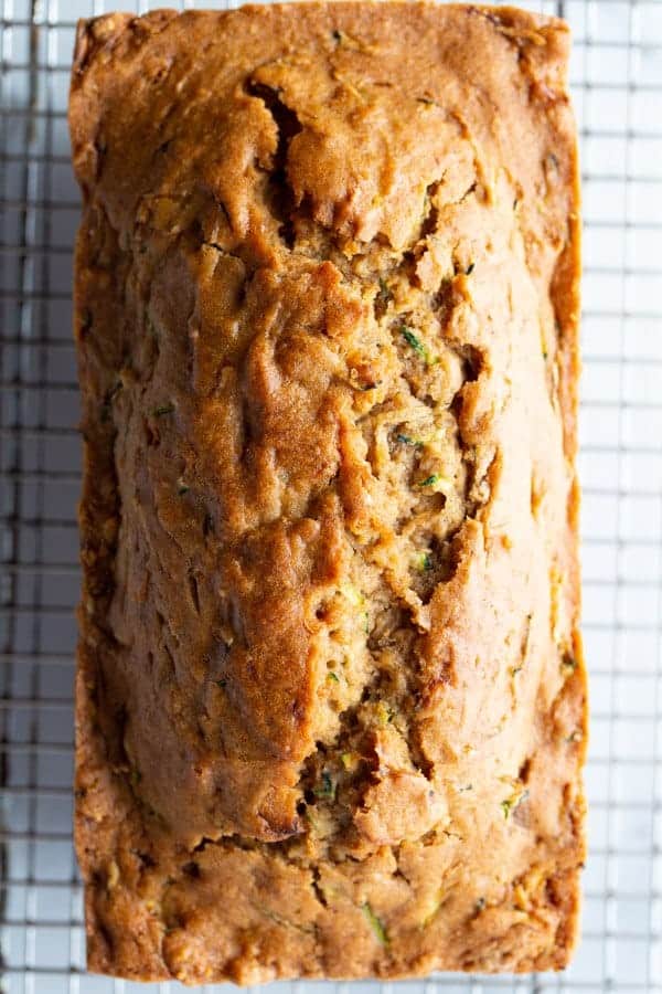 Loaf of baked gluten-free zucchini bread cooling on a rack. 