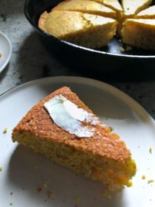 Slice of gluten-free cornbread on plate with butter on top.