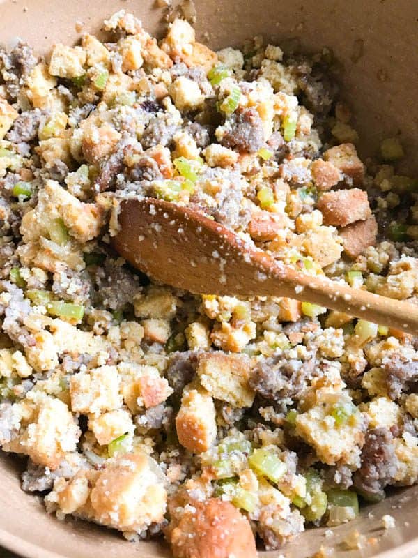 Gluten-free cornbread stuffing in mixing bowl with cooked sausage, onions, and celery.