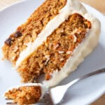 A slice of gluten-free carrot cake on a plate with a fork.