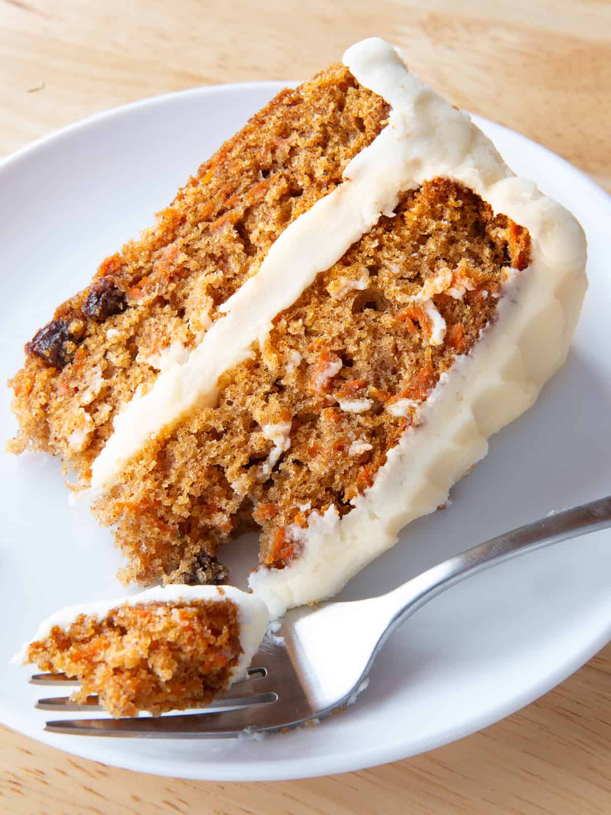 A slice of gluten-free carrot cake on a plate with a fork.