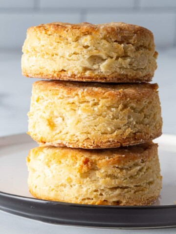 Three gluten-free biscuits stacked on a plate.