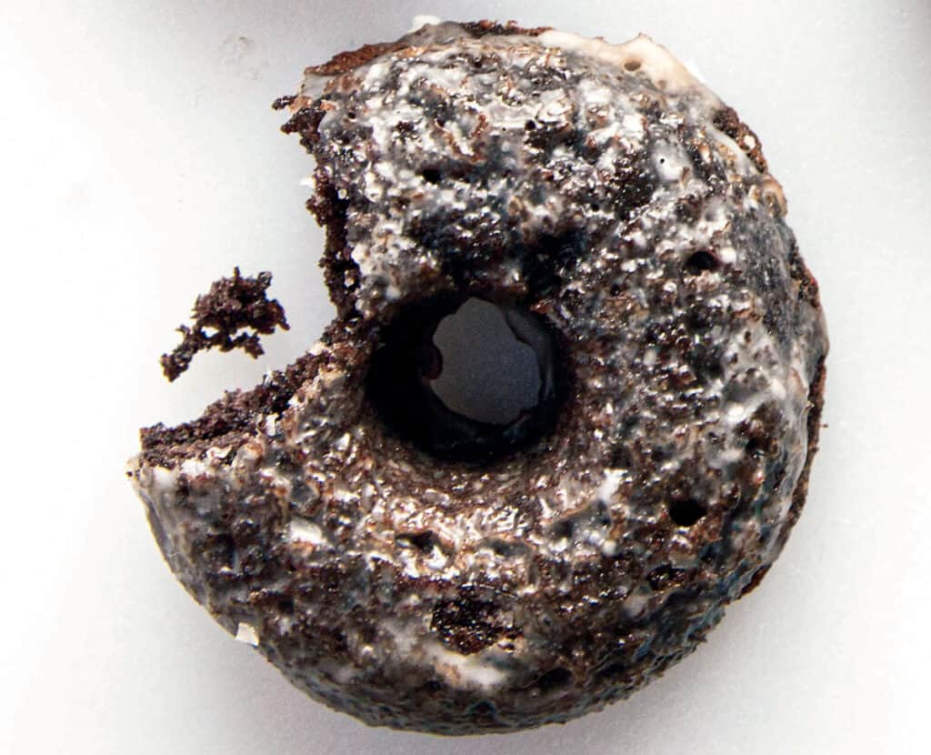 One grain-free chocolate doughnut with a bite taken out of it.